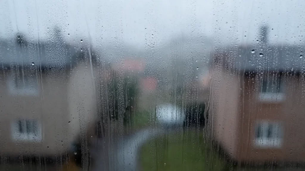 Gotas de agua y condensación recorren el cristal empañado de una ventana fría.